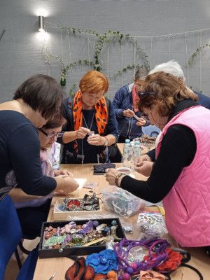 Zdjęcie ze spotkania - uczestniczki przeglądają dostępne materiały rękodzielnicze pani Danuty Bojanowskiej