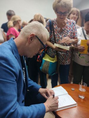 Zdjęcie Mariusza Szczygła podpisującego książki po spotkaniu autorskim
