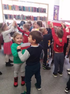 Zdjęcie z zajęć - dzieci tańczą w parach trzymając jedno białą, a drugie czerwoną kartkę, tworząc flagę Polski